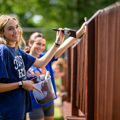 Students painting a fence on humanics in action